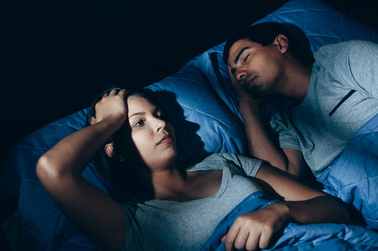Man and woman in bed with the man asleep but the woman cant sleep connection between poor sleep and Alzheimer’s risk