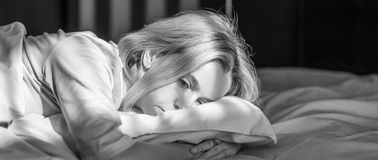 Woman experiencing night sweats trying to sleep during menopause Dark bedroom with cooling pillows for menopausal sleep comfort Middle-aged woman using blackout sleep aid to improve rest
